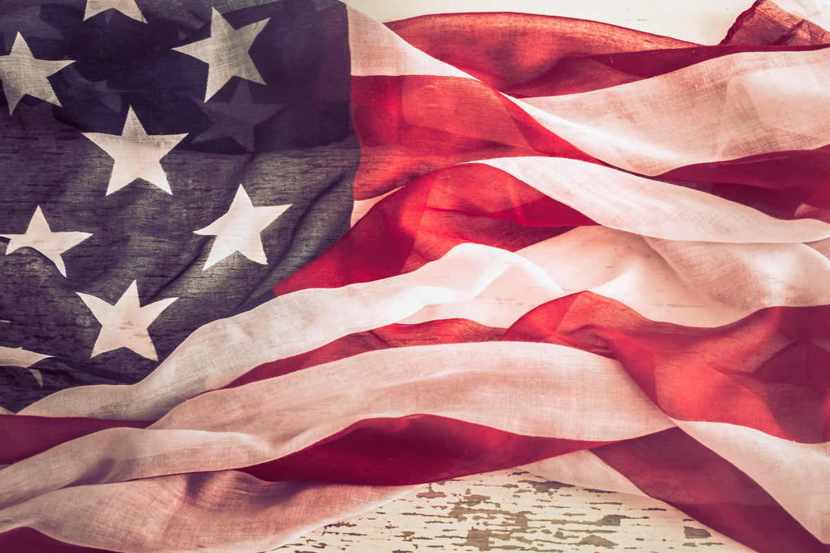 Vintage-style American flag draped across rustic wood, symbolizing patriotic pride and heritage.